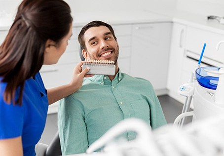 Dental assistant holding shade scale to patient's smile