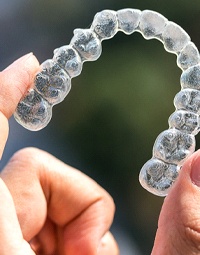 a person holding up an Invisalign tray