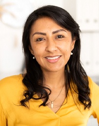 a person smiling and posing in front of a bookshelf