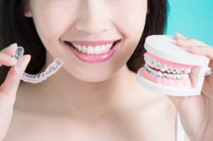 Woman holding clear tray in one hand and braces in the other