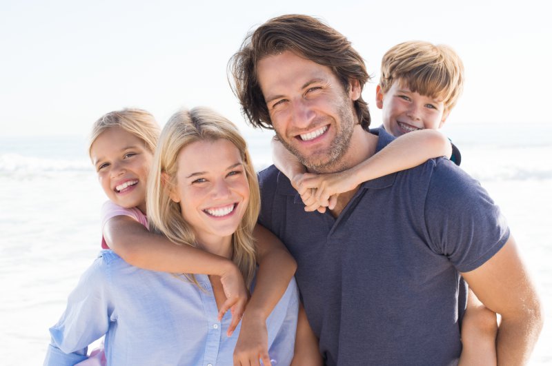 family of four hugging smiling