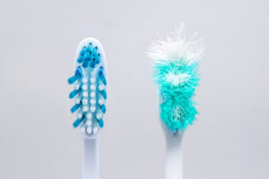 New toothbrush from Burleson dentist next to frayed, old toothbrush