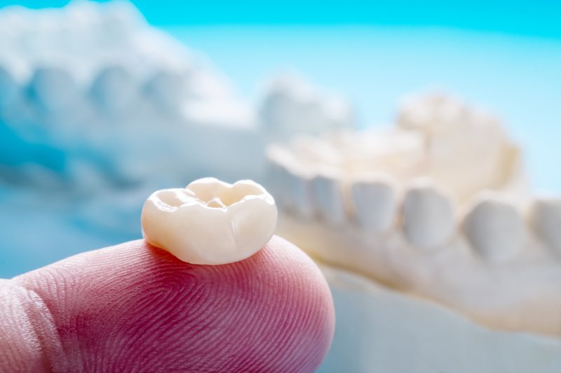 person holding dental crown on fingertip