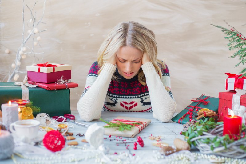 A woman suffering from holiday stress not thinking of her oral health