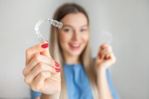 Young woman holding up Invisalign clear aligner.