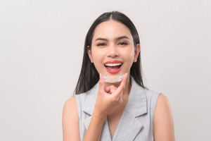 Woman in grey shirt putting in Invisalign aligner