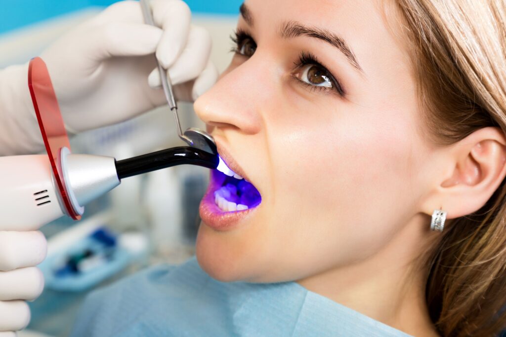 Closeup of woman's face as dentist applies UV light to harden restoration