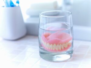 dentures in a glass of water on the bathroom counter