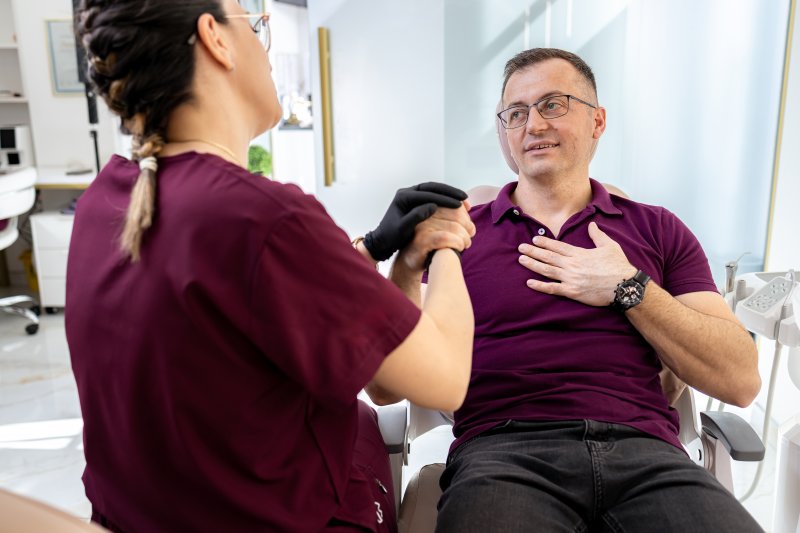 Dentist soothing nervous patient with dental anxiety